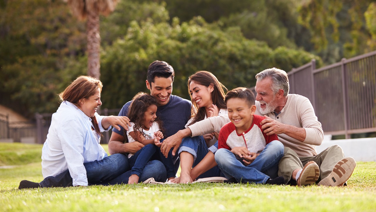a happy family with three generations sitting on the grassland in a park