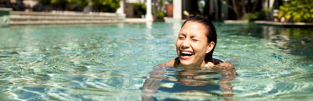 a young woman laughing so hard in a swimming pool; image used for HSBC Mauritius gold credit card page